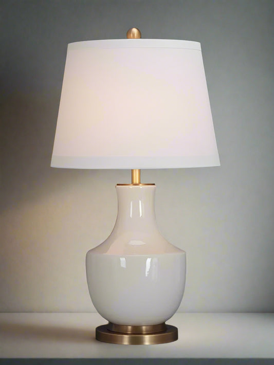 Table lamp with white shade and gold base on a gray background