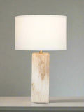 Table lamp with a beige cylindrical base and white shade on a gray background