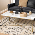 Modern marble coffee table with decor on rug in front of dark sofa